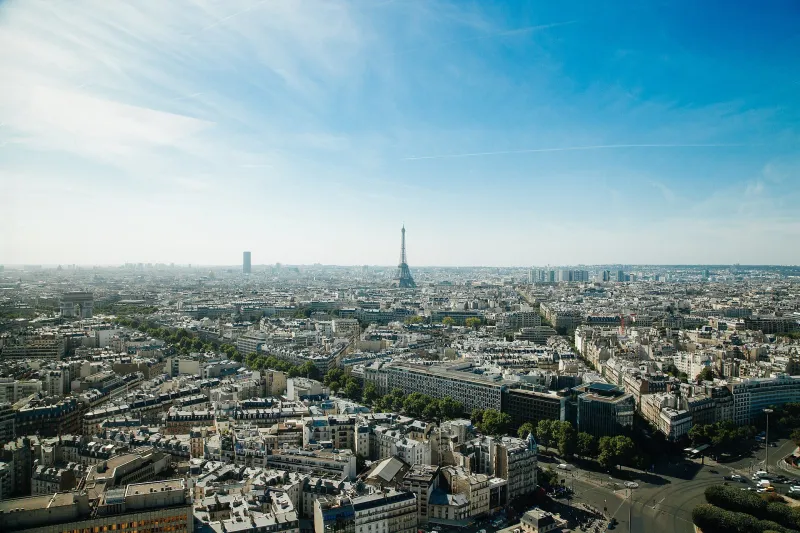 Paris rooftops and boulevards stretching towards the Eiffel Tower on a clear day.