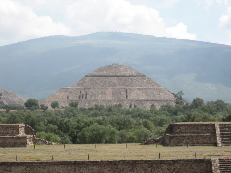 The Pyramid of the Sun at Teotihuacan seen across the plain with mountains behind.