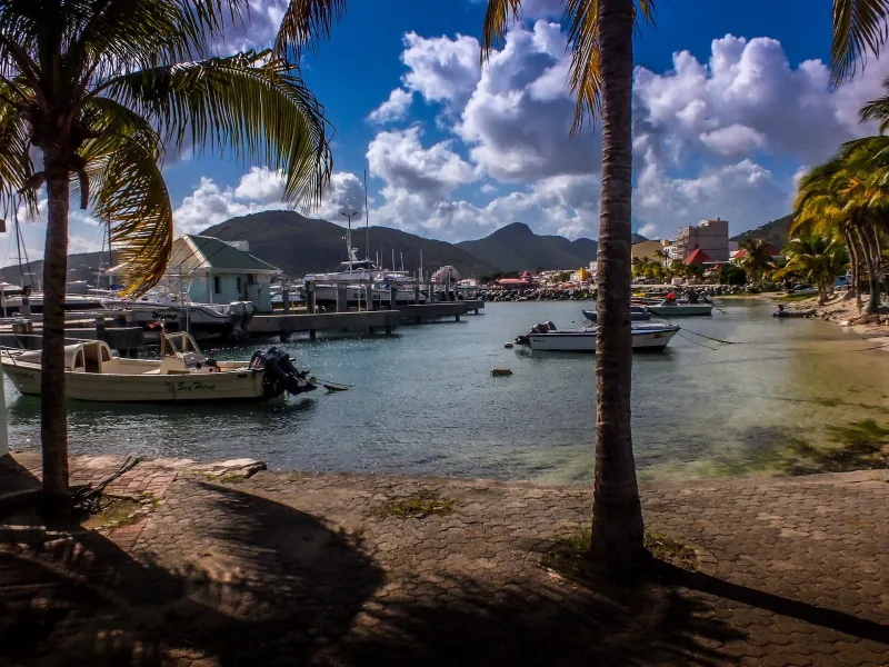 Small harbour at Philipsburg with palm trees, boats and green hills in Sint Maarten.