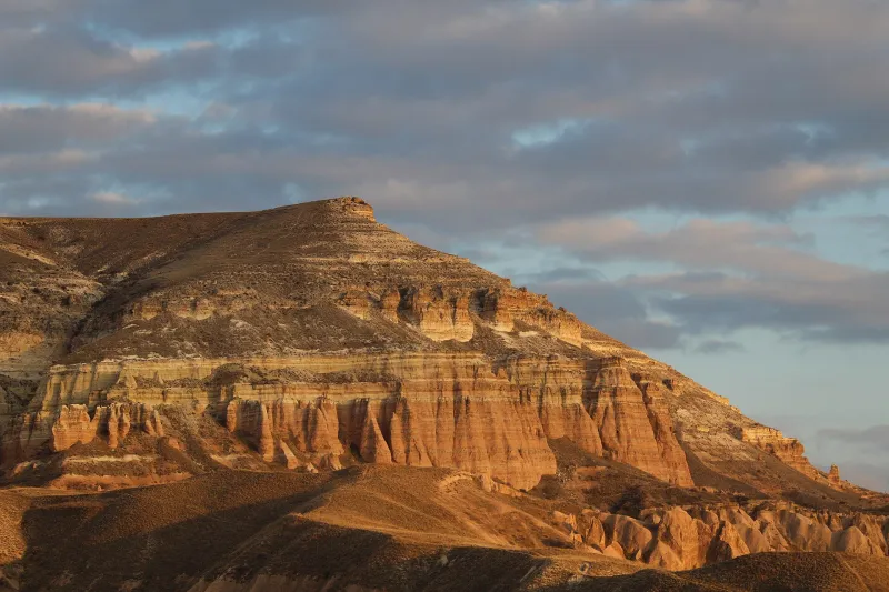 Layered orange rock formations in Cappadocia lit by evening sun.